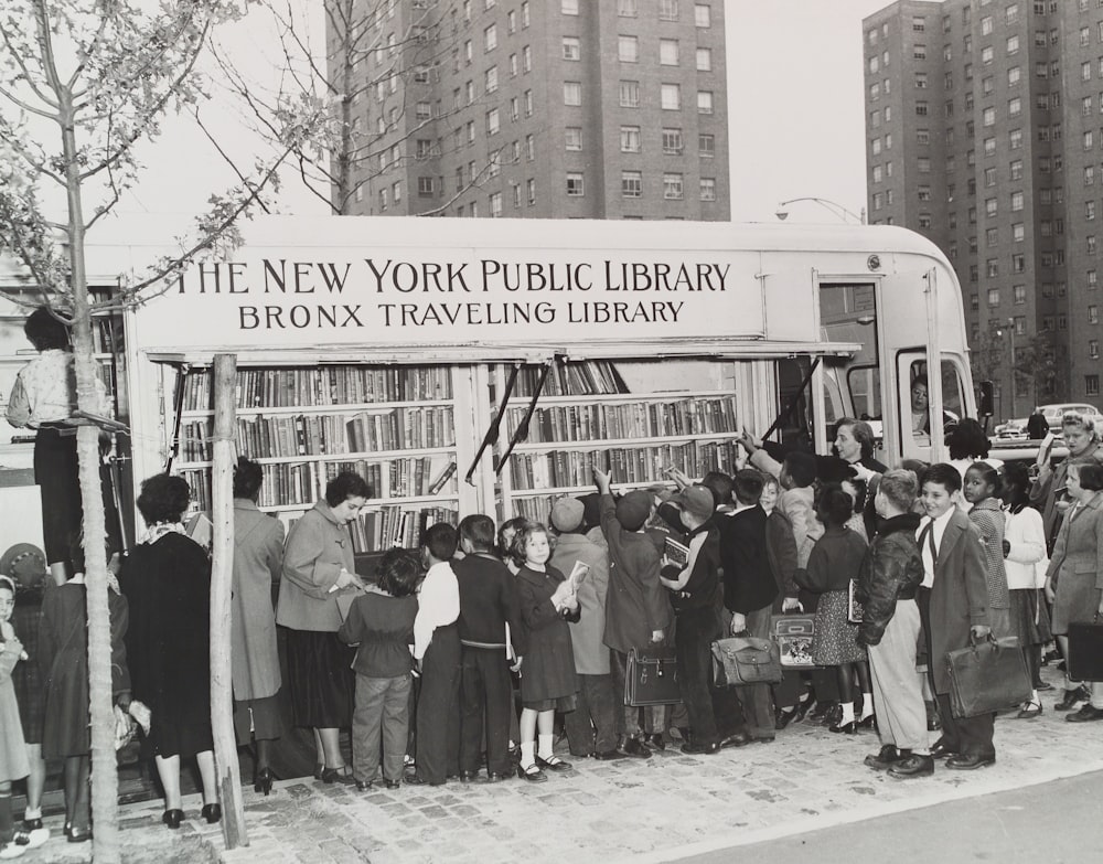 grayscale photo of people standing near the traveling New York Public Library