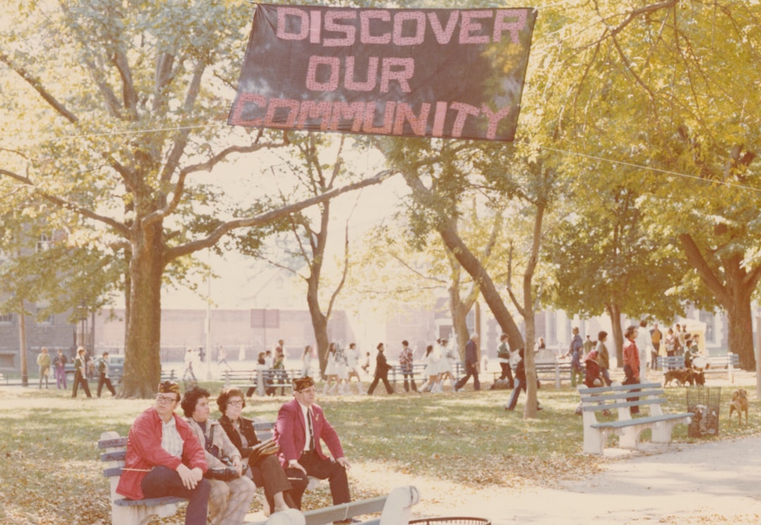 people sitting on bench in the Veteran's Park with a 'Discover our Community' sign