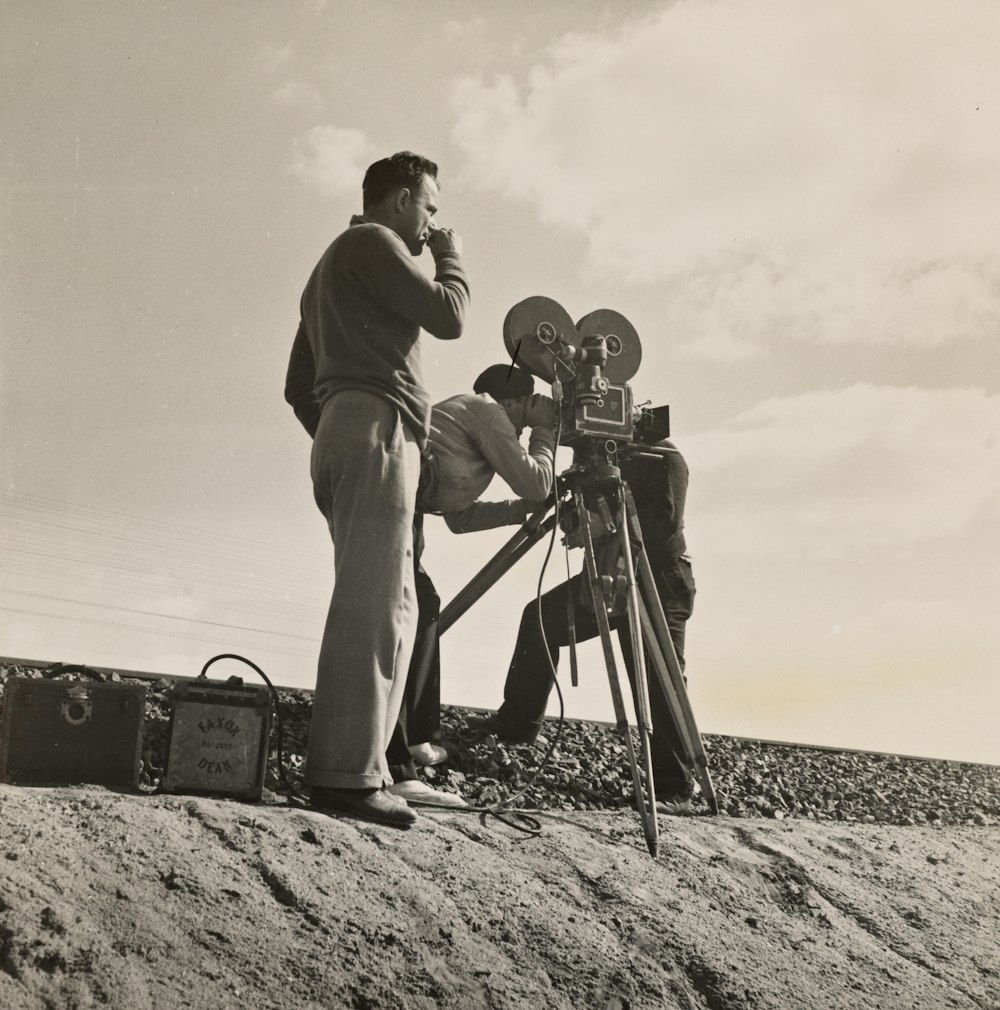two men standing near film camera while shooting a film 