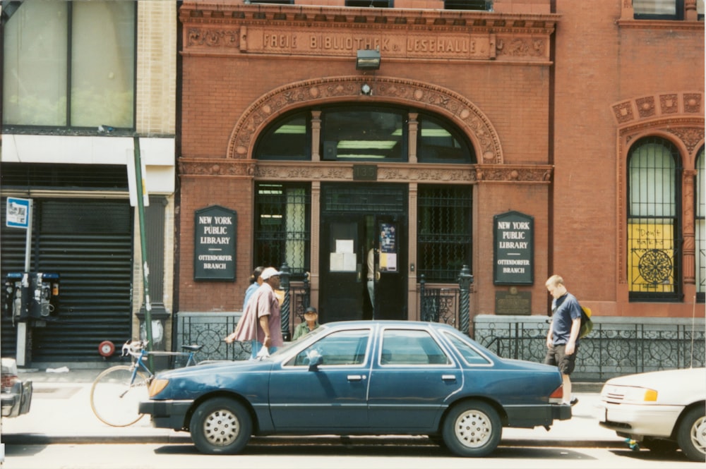 two men standing beside blue car during daytime