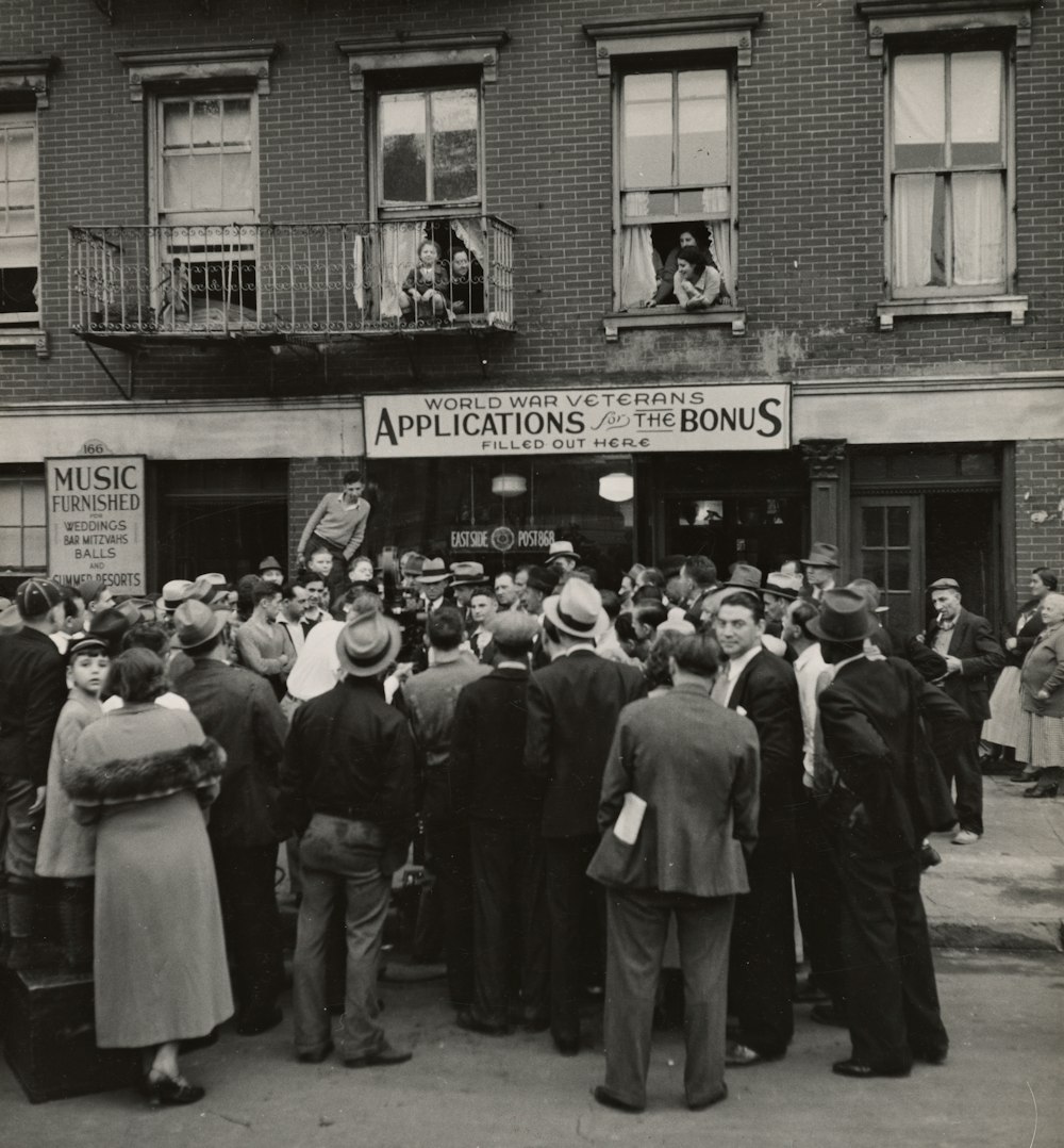 foto em tons de cinza de pessoas em pé perto do prédio dos correios