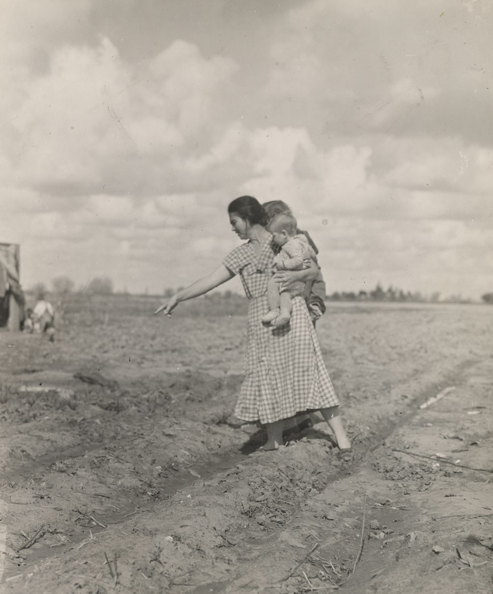 woman standing on soil while carrying a child on her hip