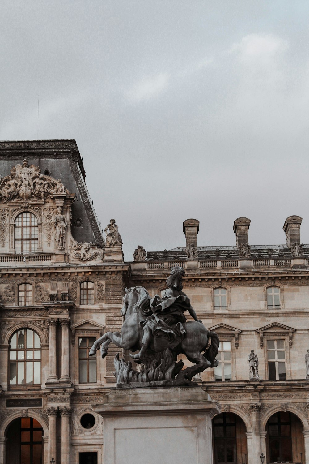 man riding horse statue near brown concrete building during daytime