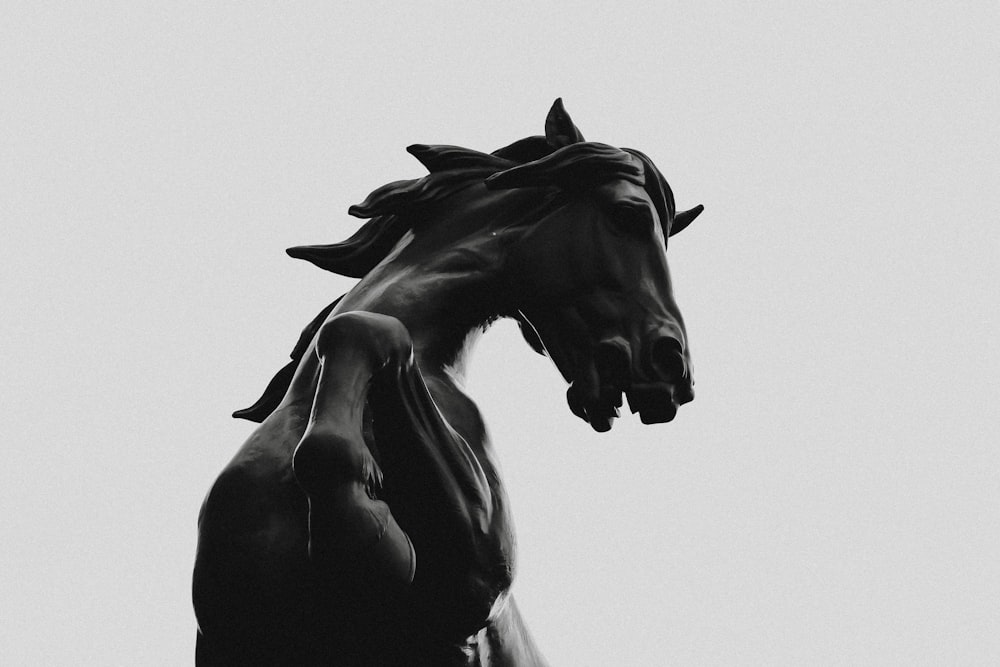 black horse statue in grayscale photography