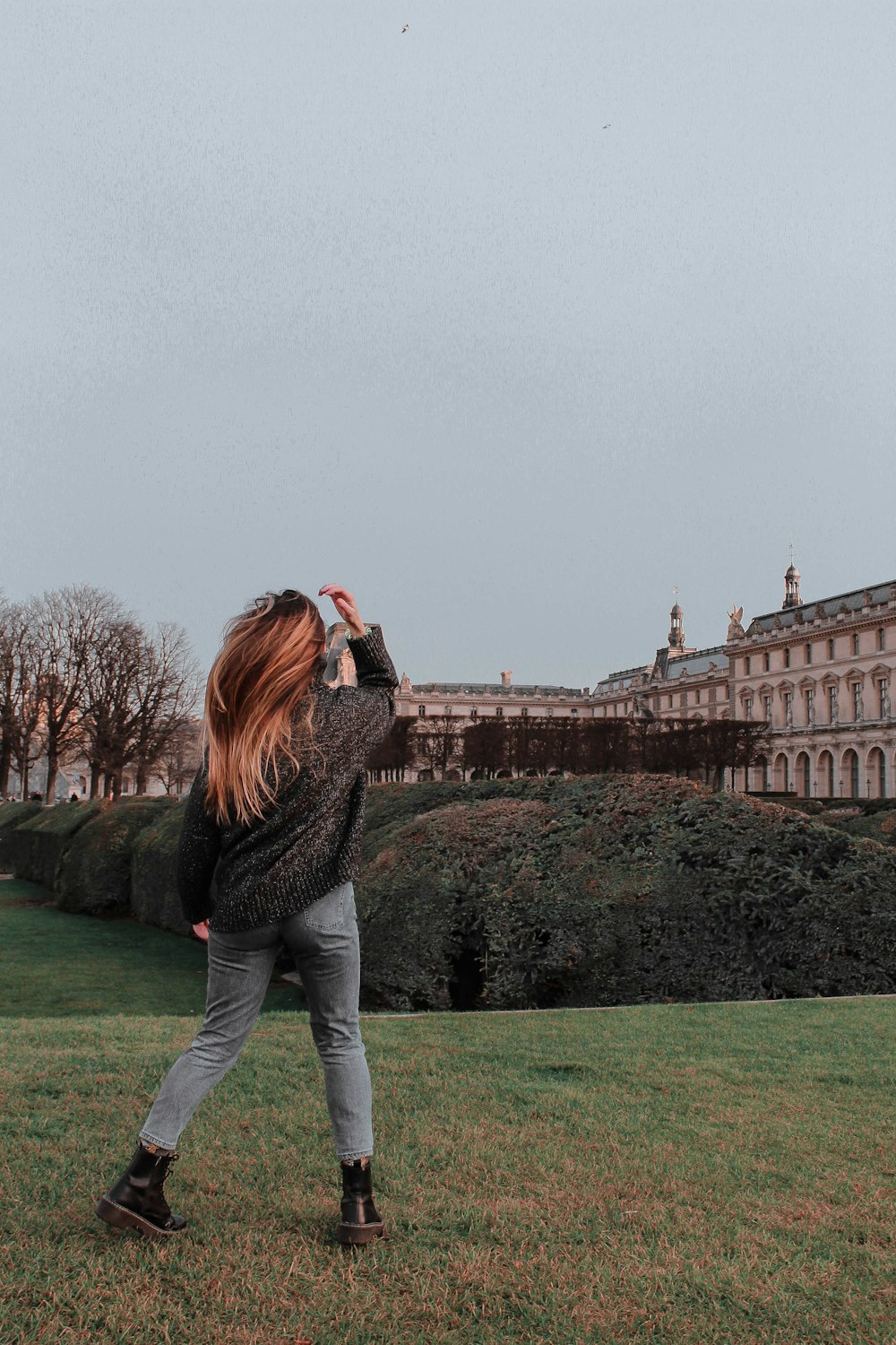 woman in black sweater and gray pants standing on green grass field during daytime