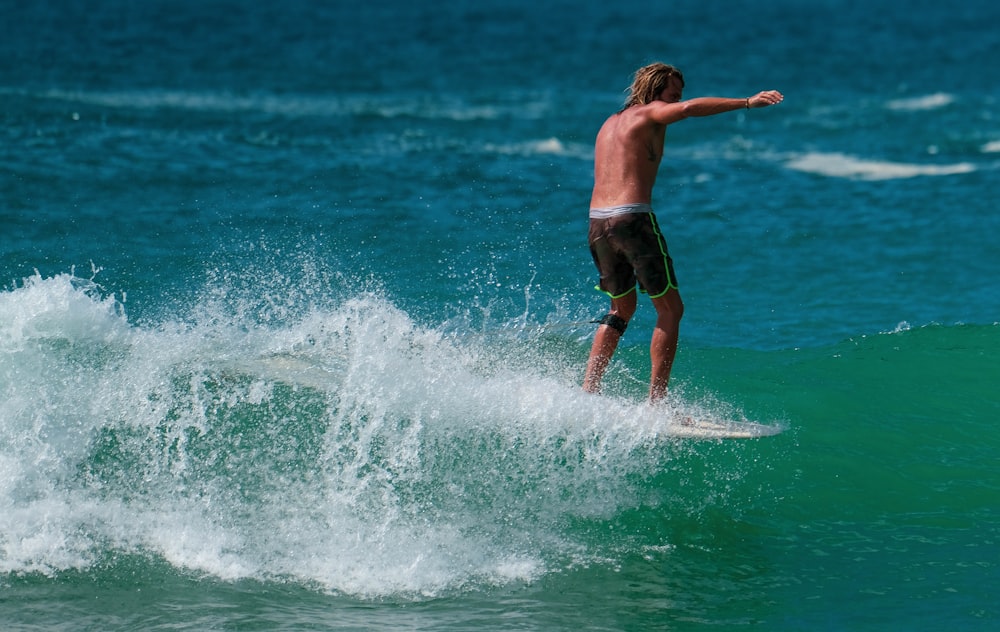 man in black shorts surfing on sea waves during daytime