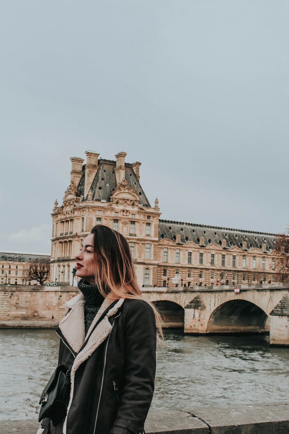 woman in black jacket standing near brown concrete building during daytime