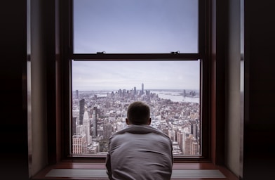 man in gray shirt looking at city buildings during daytime