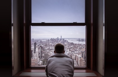 man in gray shirt looking at city buildings during daytime