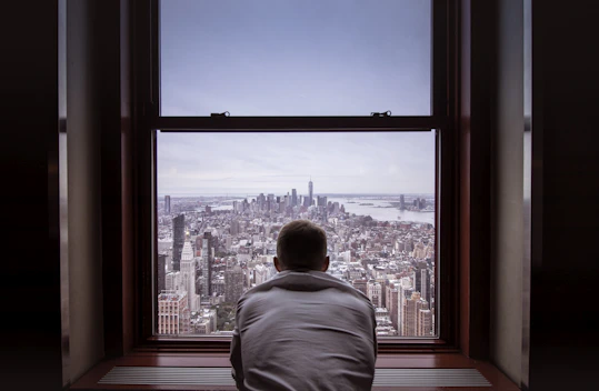 man in gray shirt looking at city buildings during daytime