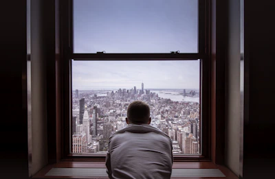 man in gray shirt looking at city buildings during daytime