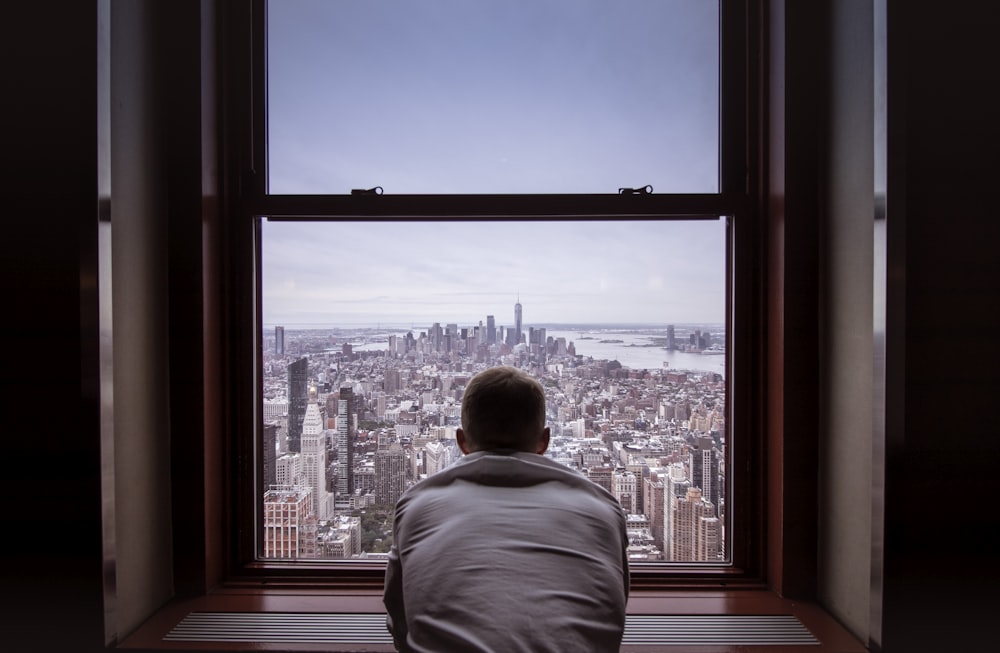 uomo in camicia grigia che guarda gli edifici della città durante il giorno