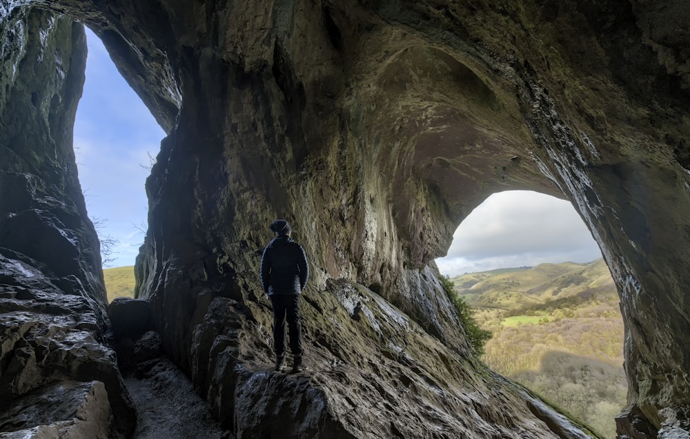 man in black jacket standing on brown rock formation during daytime