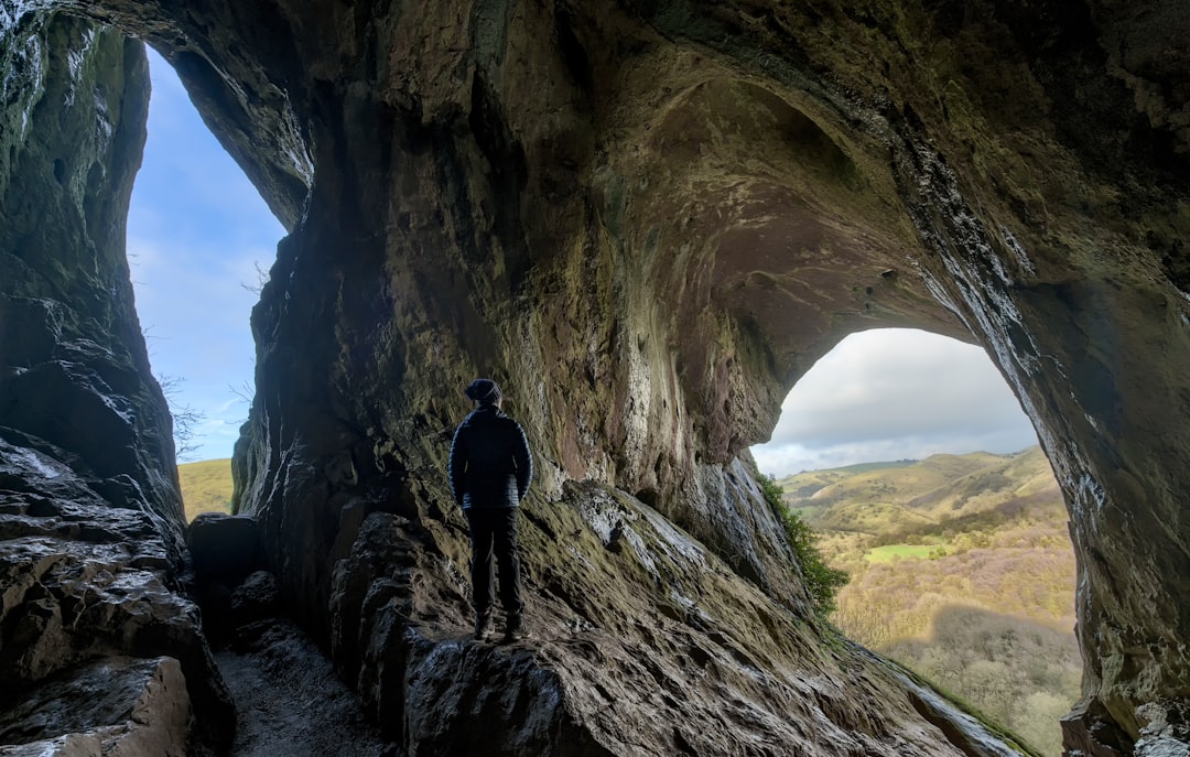 man in black jacket standing on brown rock formation during daytime