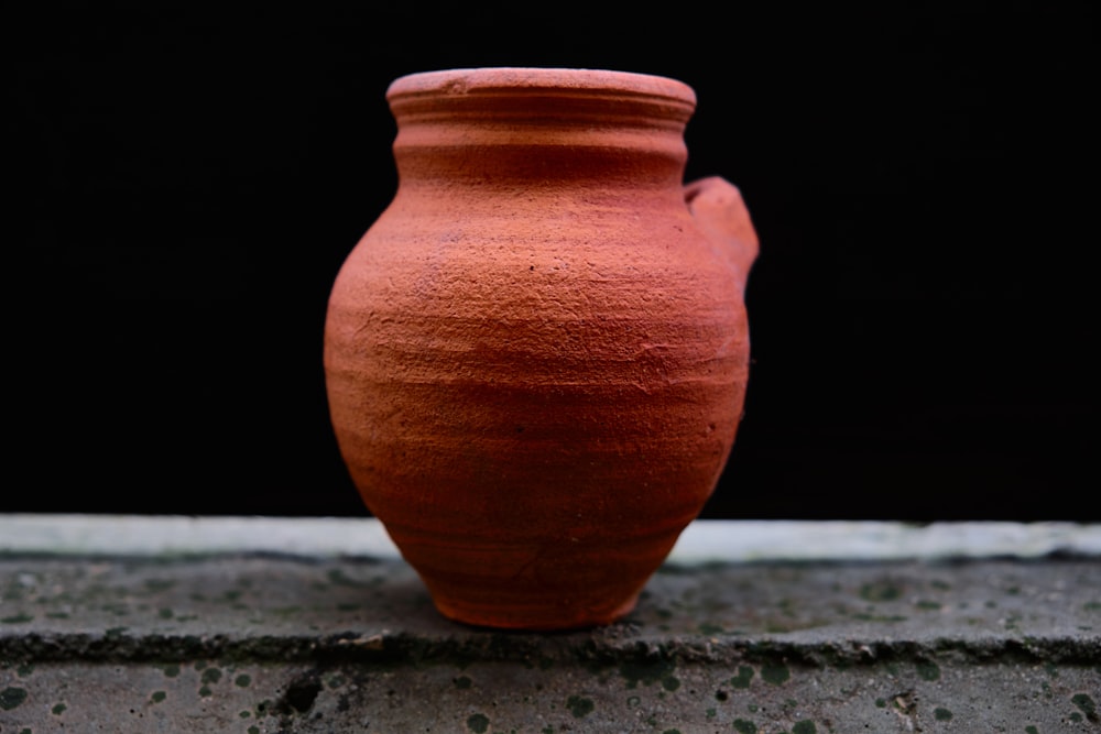 brown clay vase on gray concrete surface