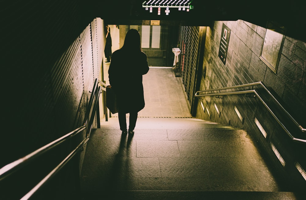woman in black coat walking on hallway