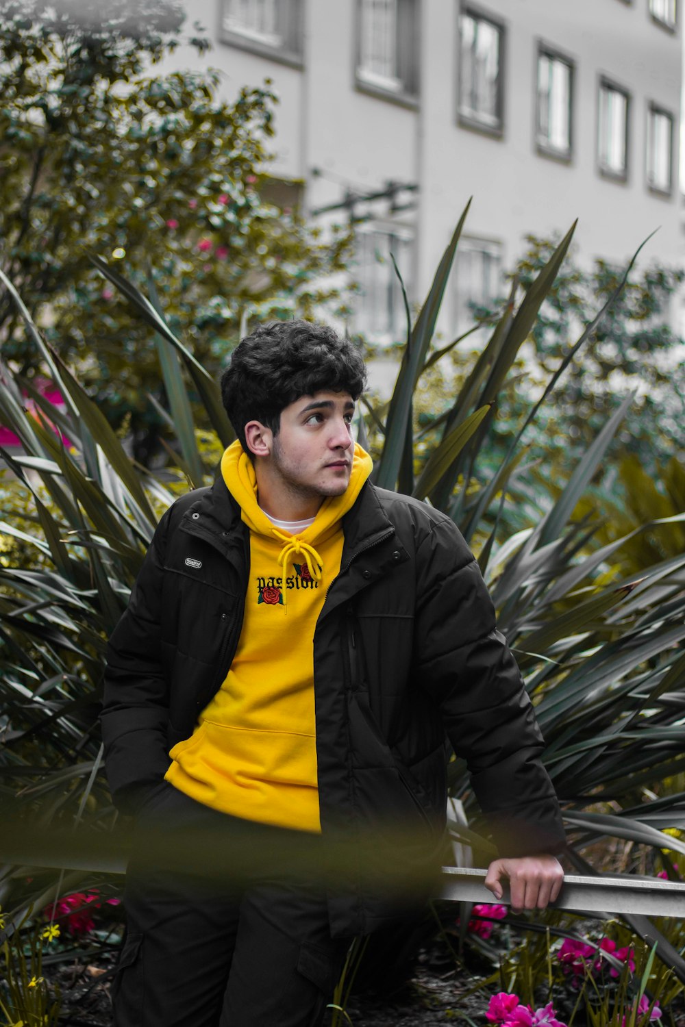 man in black leather jacket standing near green plants during daytime