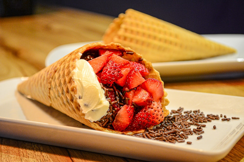 waffle marrom com sorvete vermelho e branco em placa de cerâmica branca