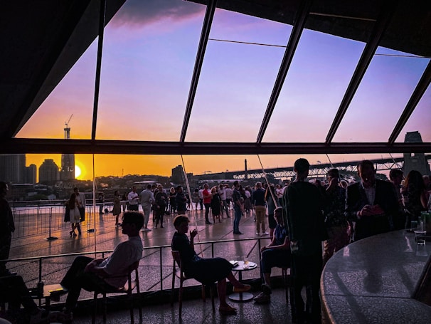 Attendees enjoying a relaxed social hour with city skyline visible through large windows.