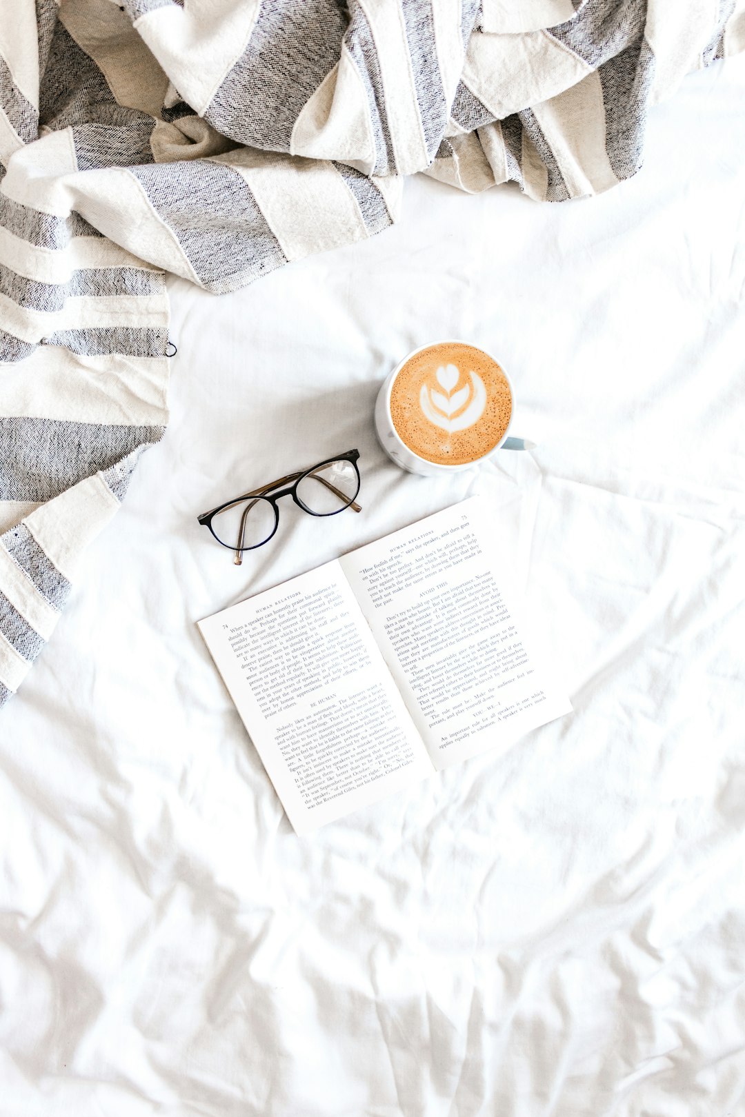 black framed eyeglasses beside white ceramic mug on white textile