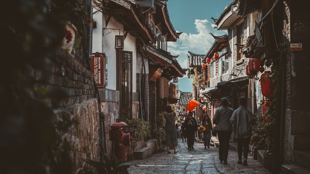 people walking on street between houses under blue sky during daytime