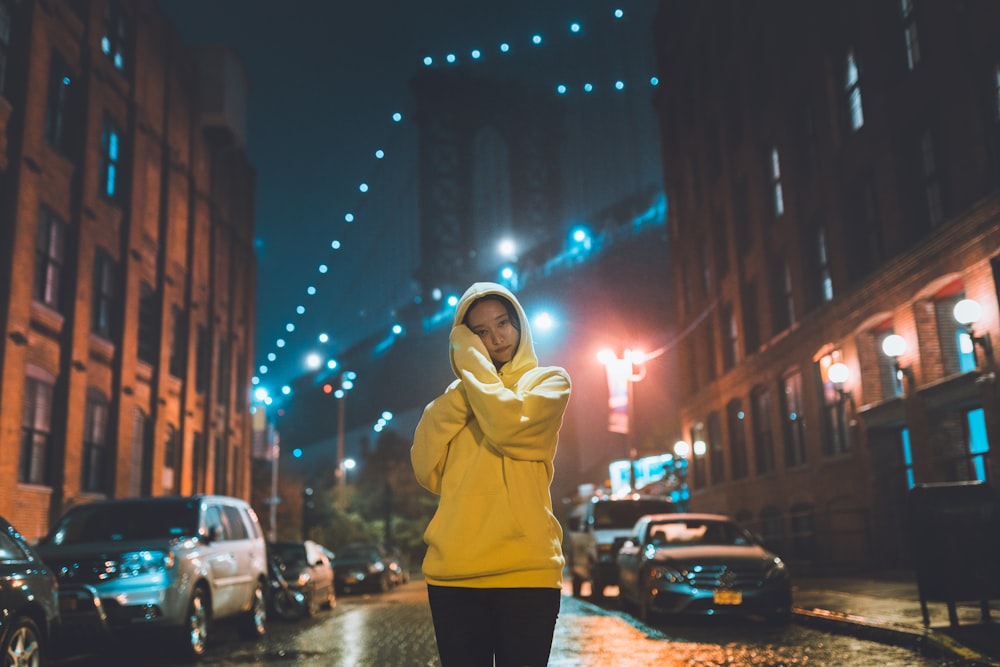 woman in beige hoodie standing on street during night time