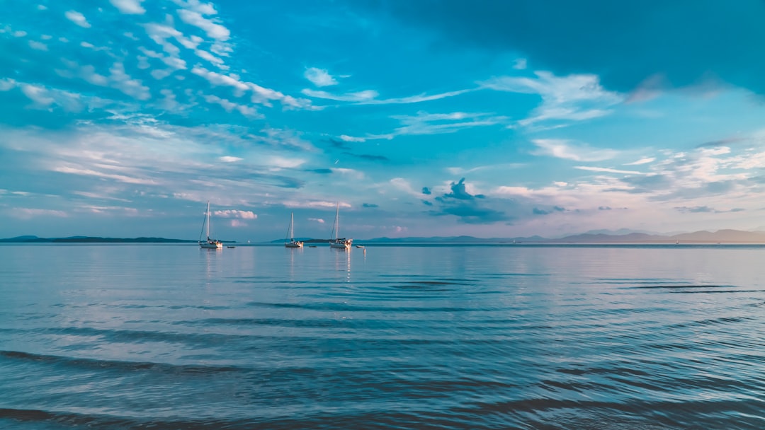 white boat on sea under blue sky and white clouds during daytime