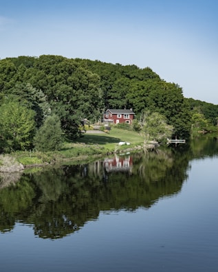 A peaceful lakeside property with trees reflecting on the water.