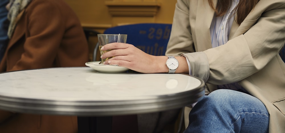 person in white long sleeve shirt holding clear drinking glass