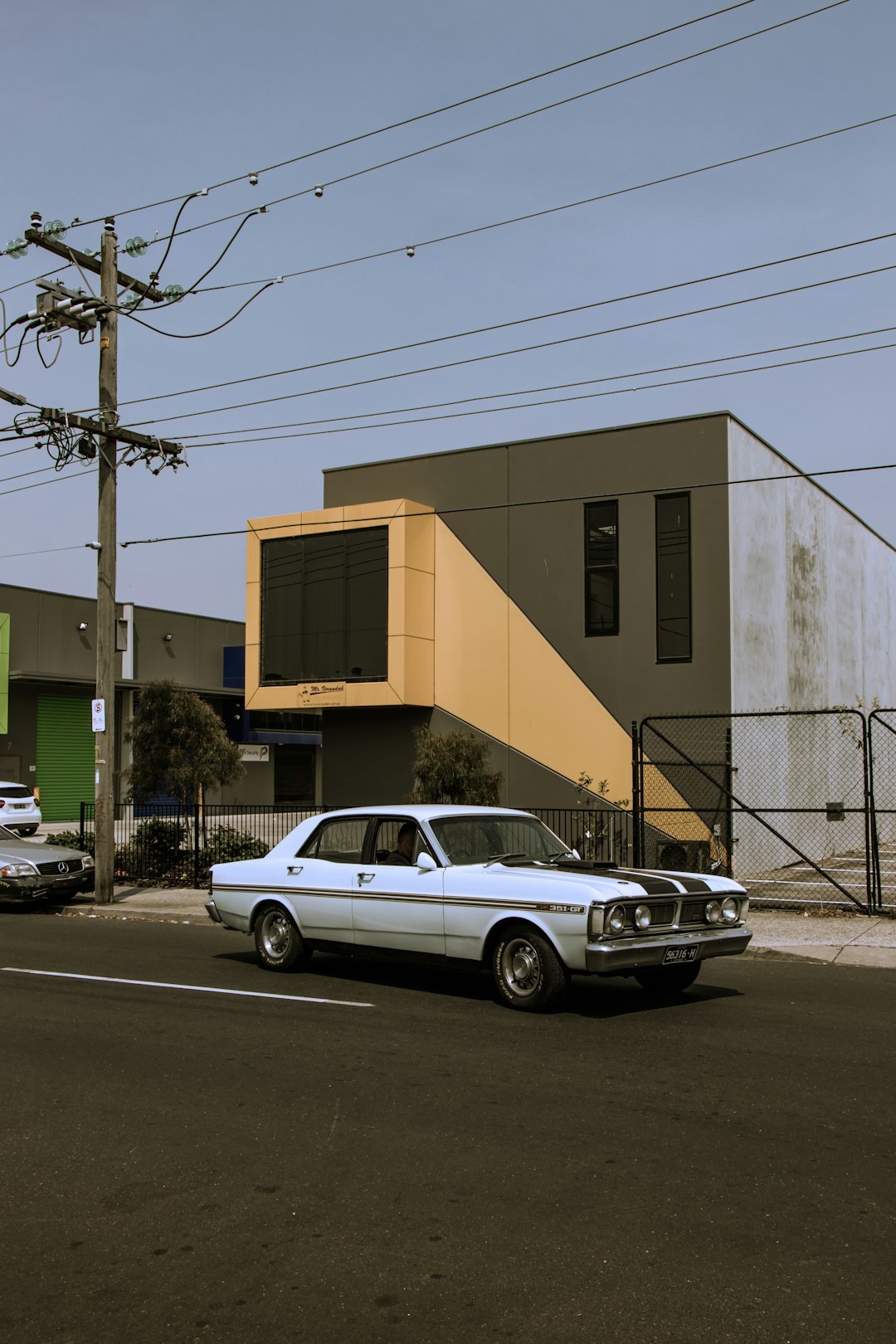 white sedan parked beside white concrete building during daytime