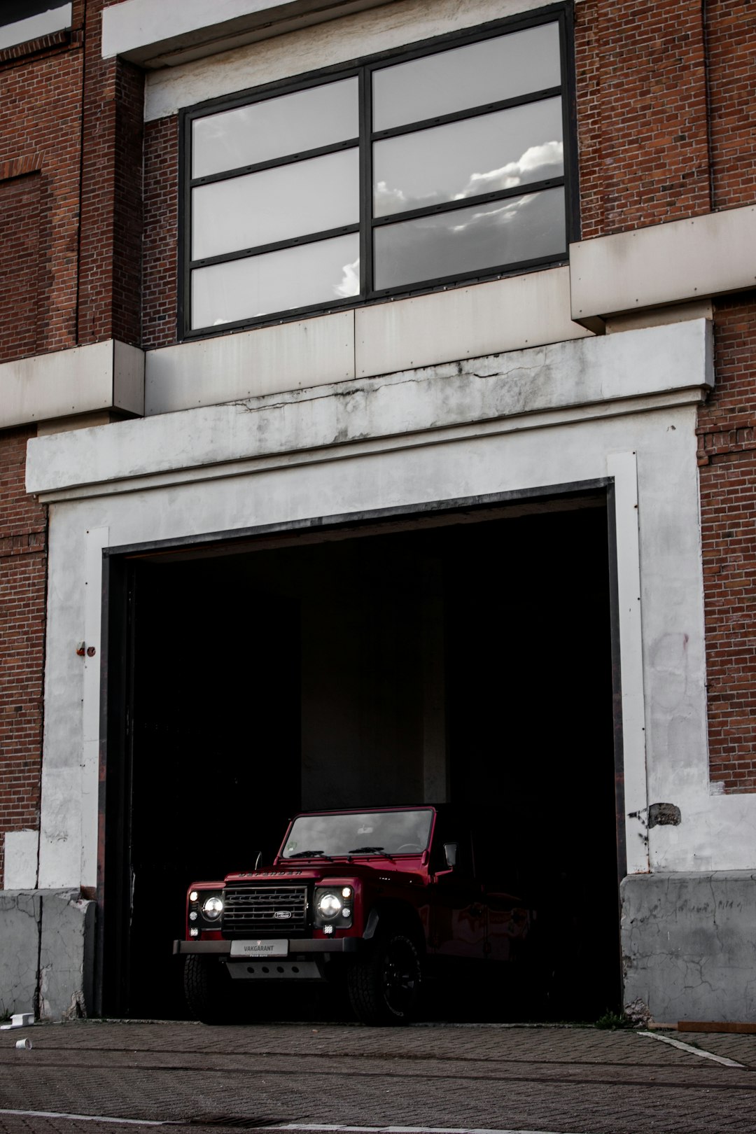 red car parked in front of white concrete building