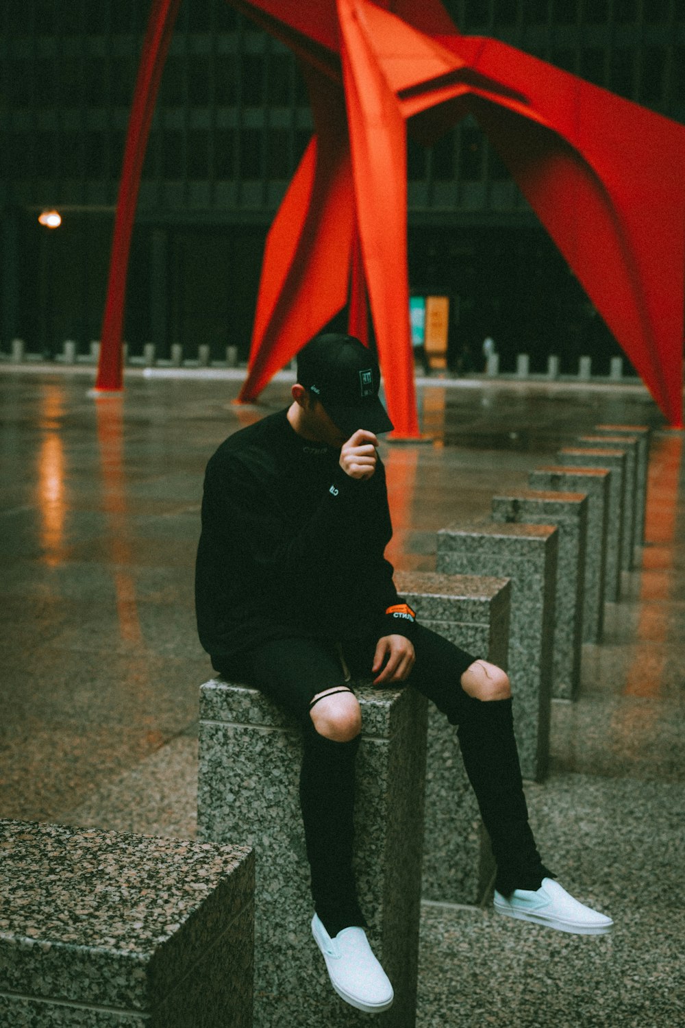 man in black jacket and black knit cap sitting on gray concrete bench