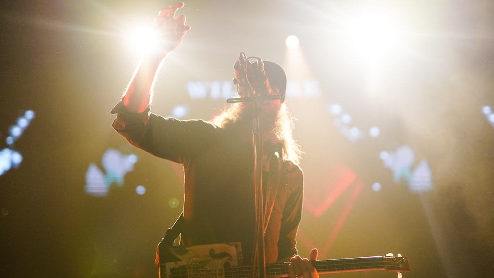 man in black jacket singing on stage