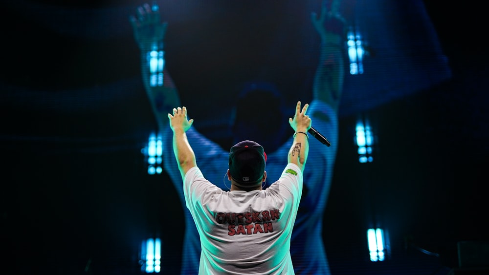 man in white and black crew neck t-shirt raising his hands