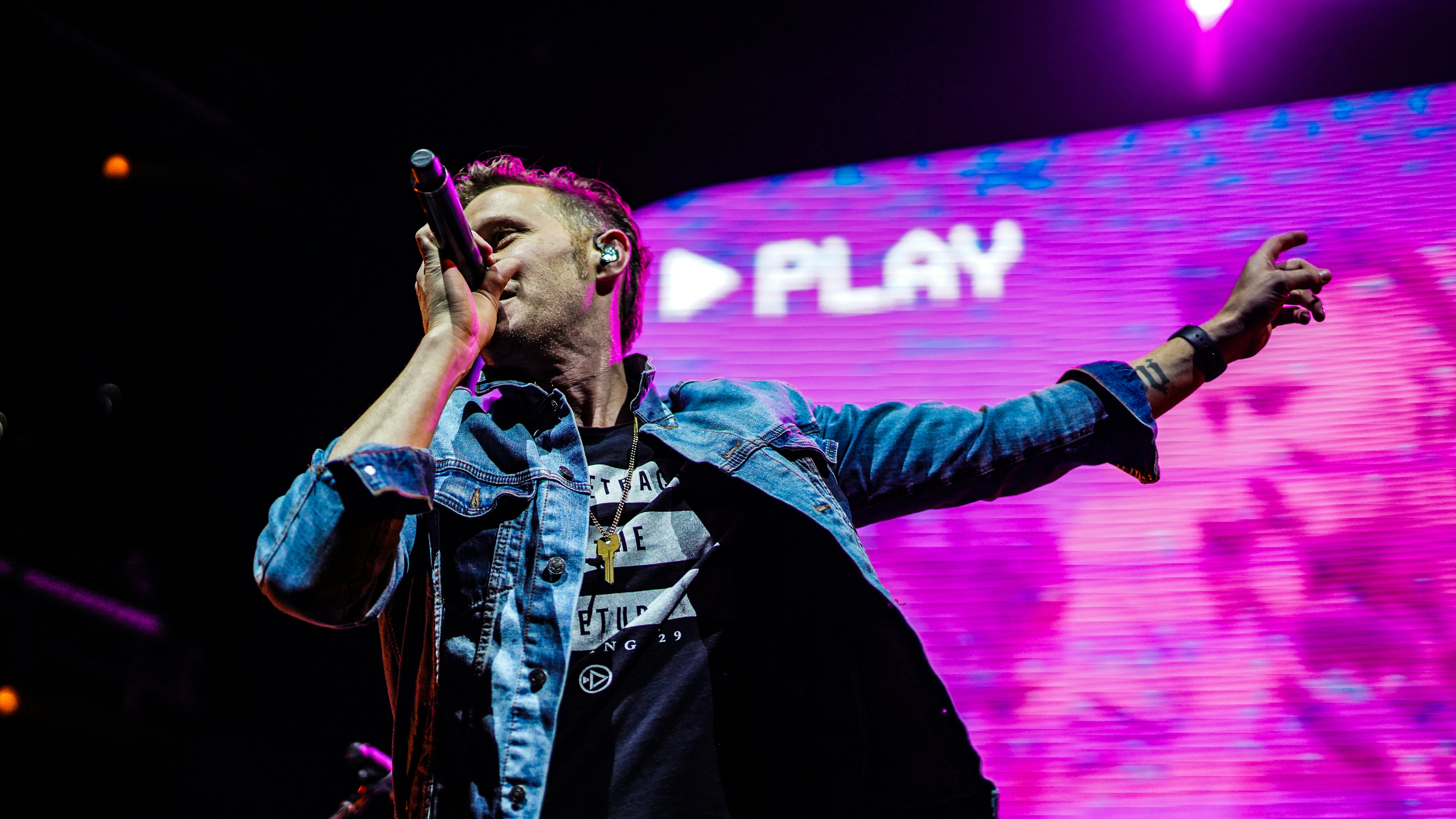 man in black jacket singing on stage