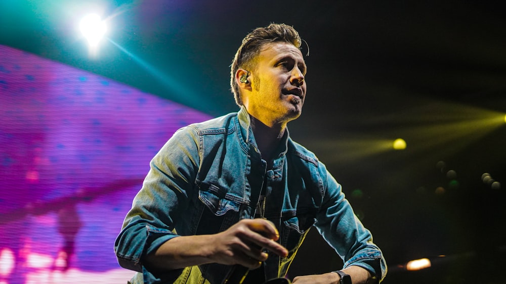 man in blue denim jacket holding smartphone