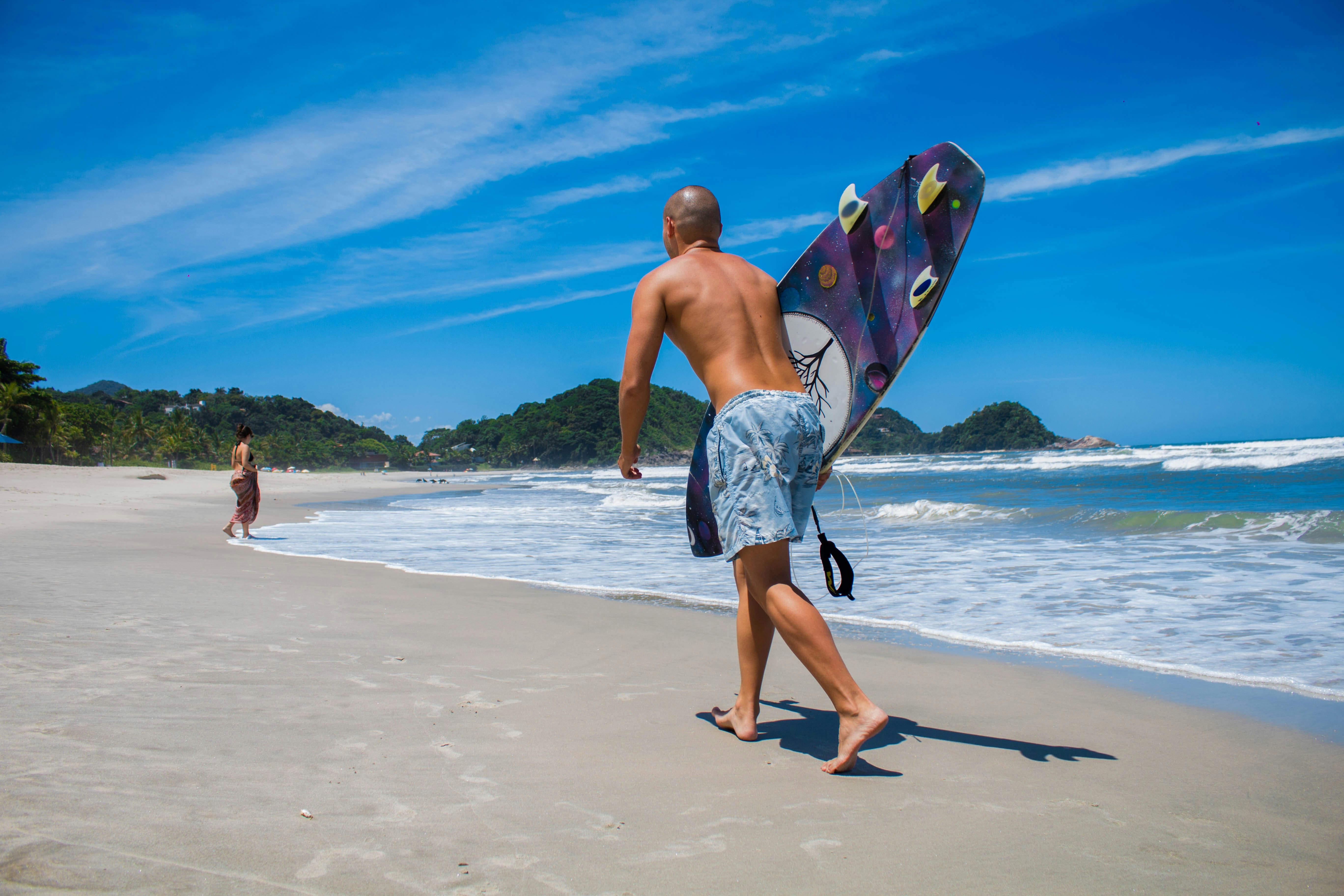 man in blue and white shorts walking on beach during daytime