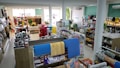 A well-organized store interior with neatly arranged products. Various home goods and decorations are displayed, including kitchenware, artificial flowers, and textiles. Shelves are filled with neatly stacked items, and the store is brightly lit with natural and artificial light.
