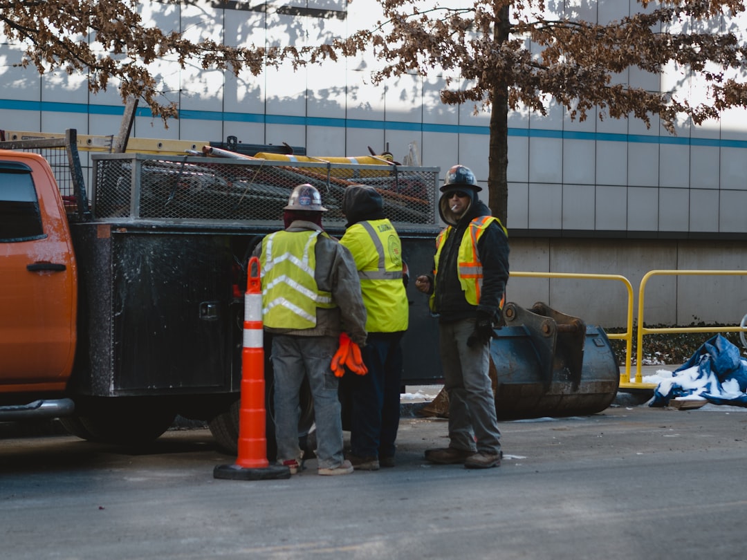 3 men in green and yellow jacket standing near black truck during daytime