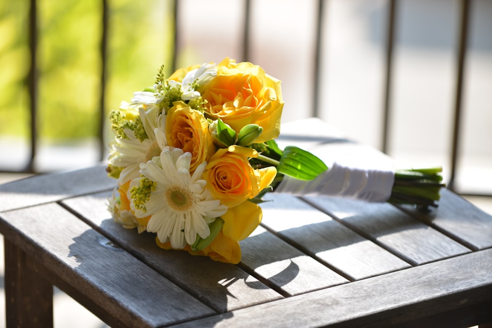 yellow and white flower bouquet on brown wooden table