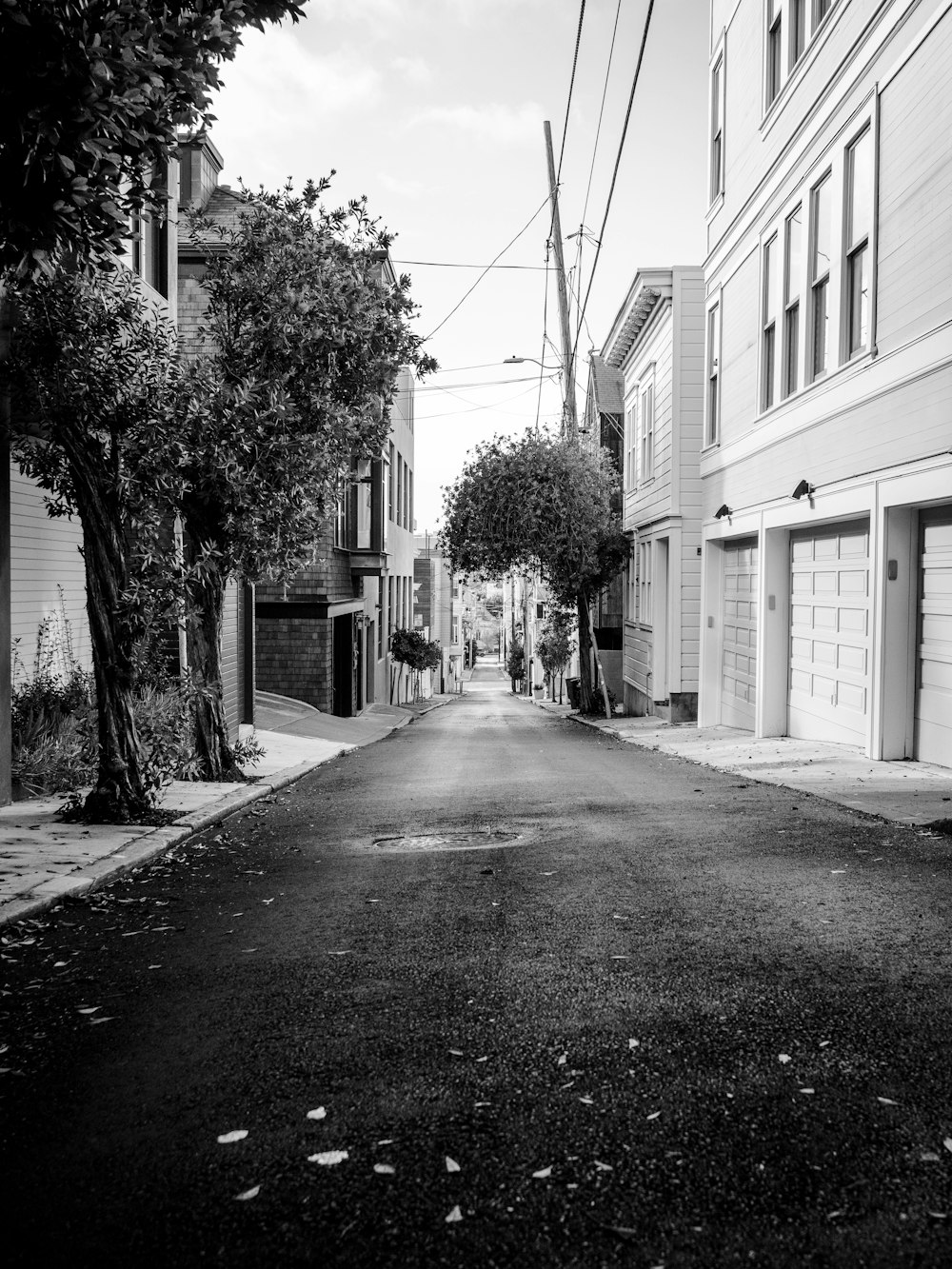 grayscale photo of empty road between houses