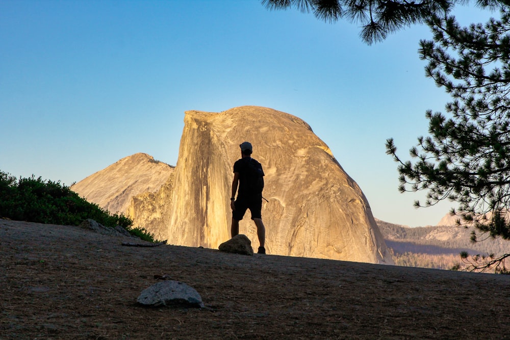 person standing on rock near brown mountain during daytime