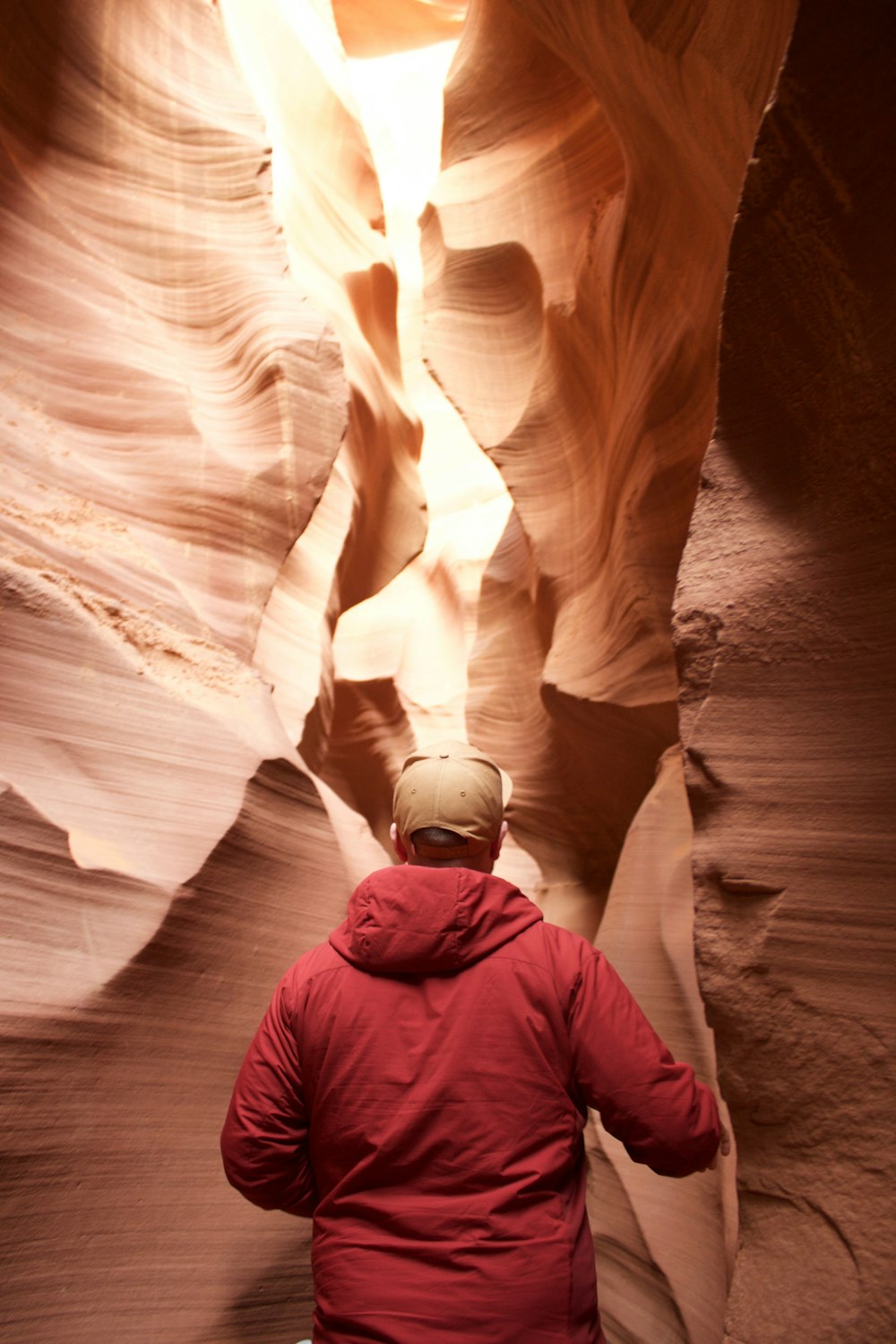 man in blue jacket standing on brown rock formation during daytime