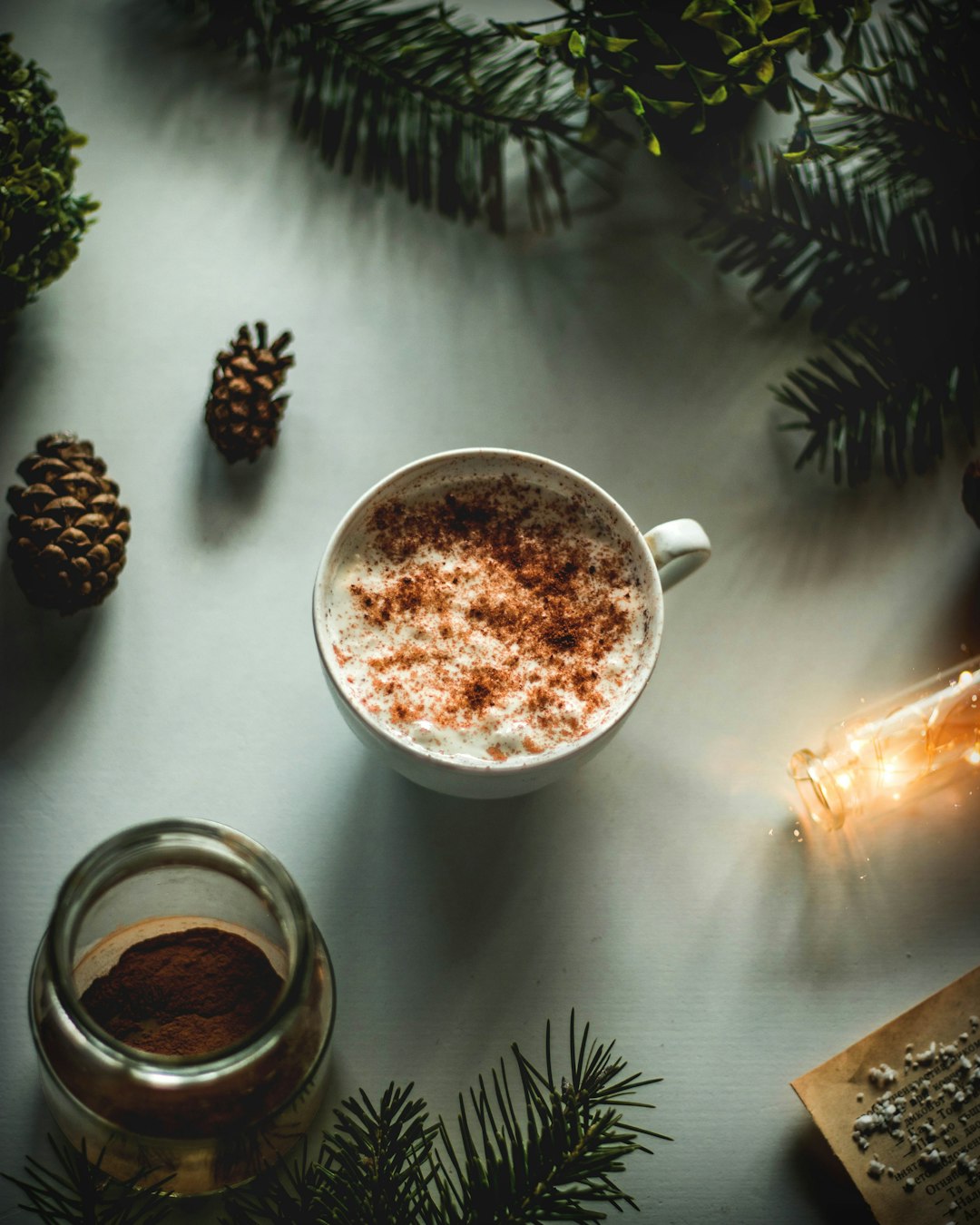 white ceramic mug with coffee beside pine cone