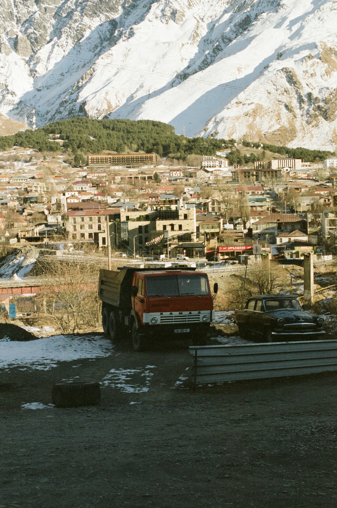 red and black truck on road near houses and mountain during daytime