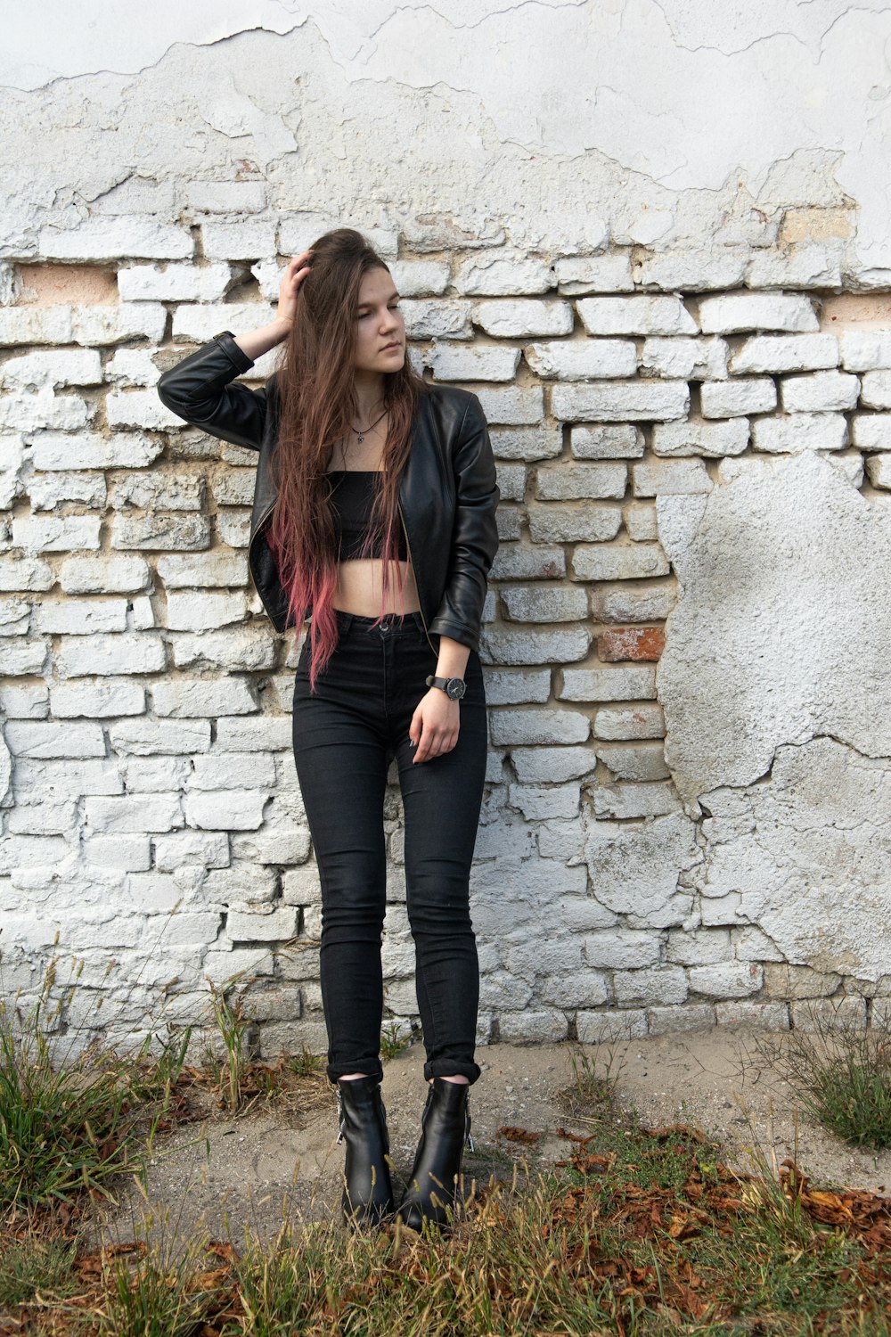 Foto Mujer con chaqueta de cuero negro y pantalones negros de pie junto a  la pared de ladrillo durante el día – Imagen Gris gratis en Unsplash