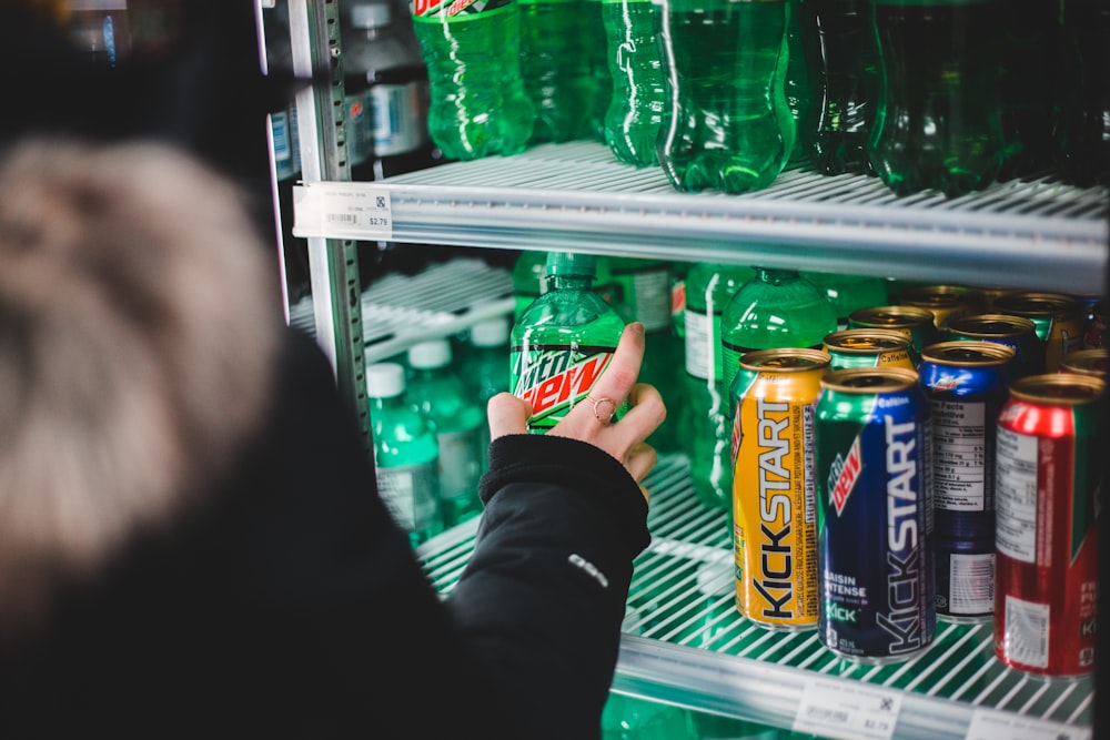 person holding sprite and orange soda cans