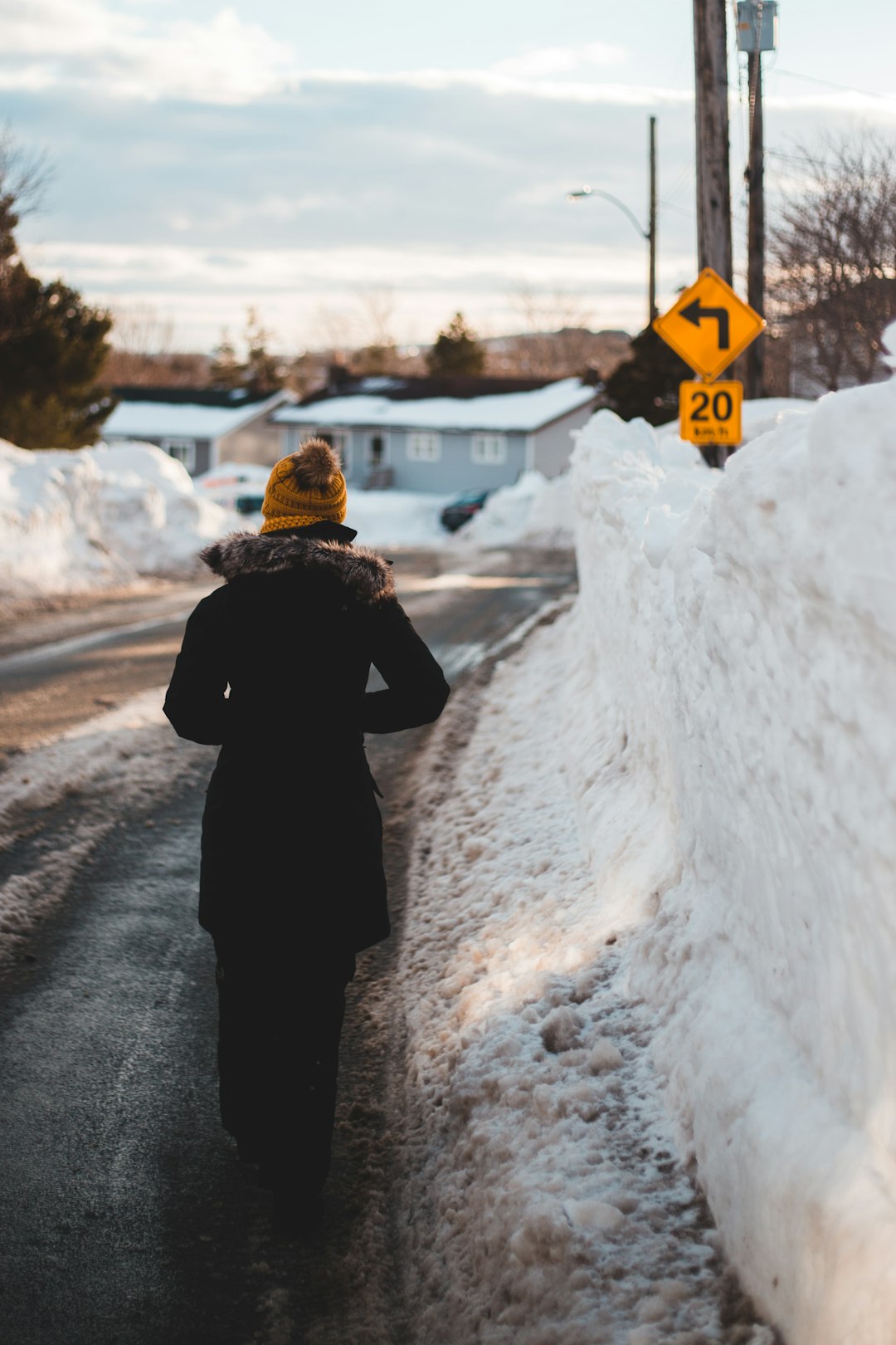 person in black coat standing on snow covered road during daytime