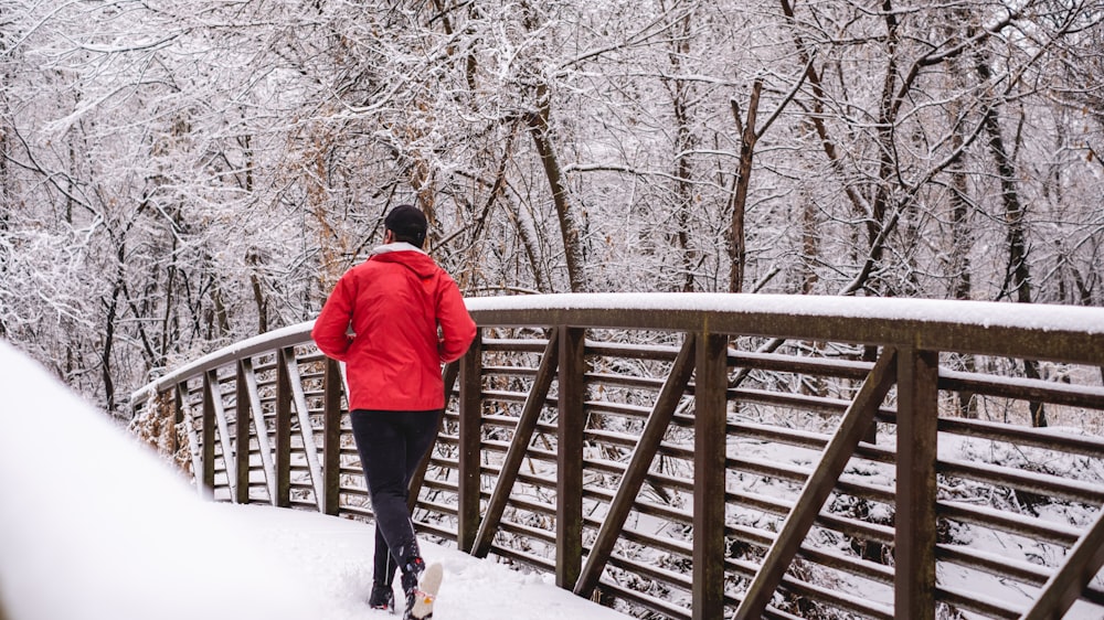 person in red jacket standing on snow covered ground during daytime