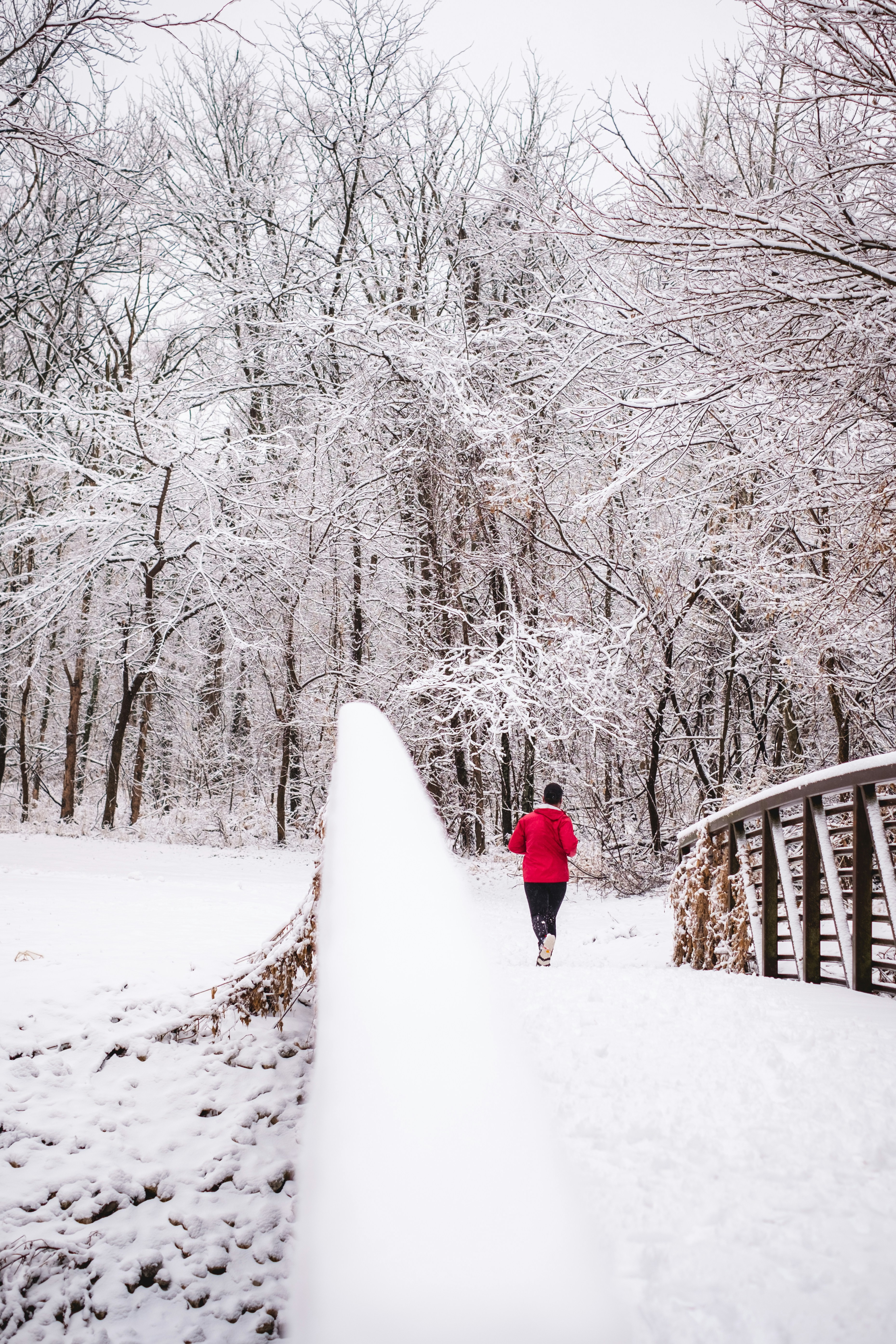 person in red jacket walking on snow covered pathway